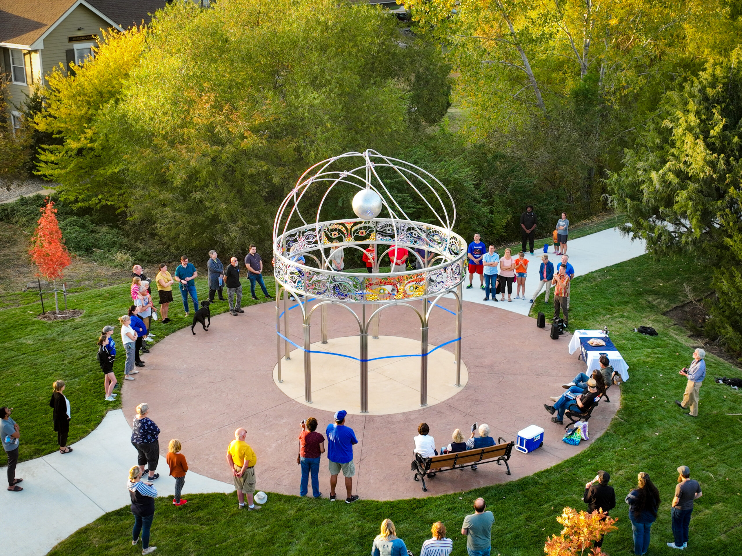 Picture of people gathered around "Through Other Eyes," a public artwork near the Lawrence Police Department Headquarters created by Joe O'Connell of Creative Machines studio.